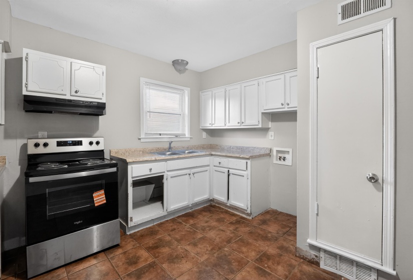 Kitchen featuring white cabinetry, light-toned countertops, a stainless steel and black range, a double basin sink, and brown floor tiles
