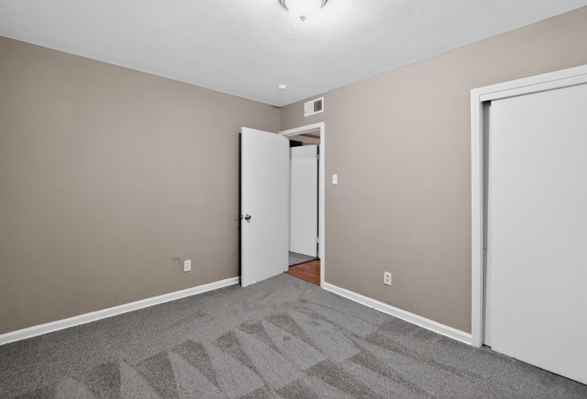 Carpeted room featuring neutral-toned walls, white trim, a ceiling light fixture, a white interior door, and a white sliding closet door
