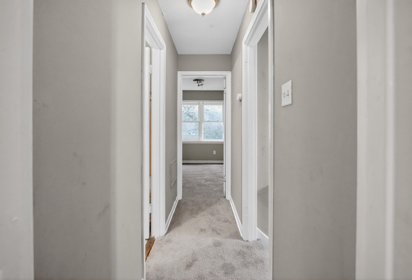 Carpeted hallway with light gray walls, white trim, and an overhead flush mount light fixture