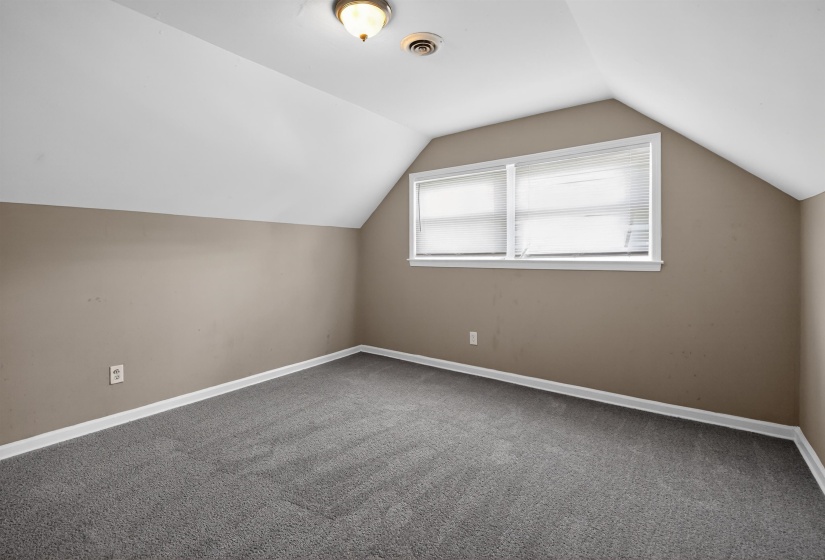 Attic room with sloped ceilings, neutral wall paint, and gray carpet flooring