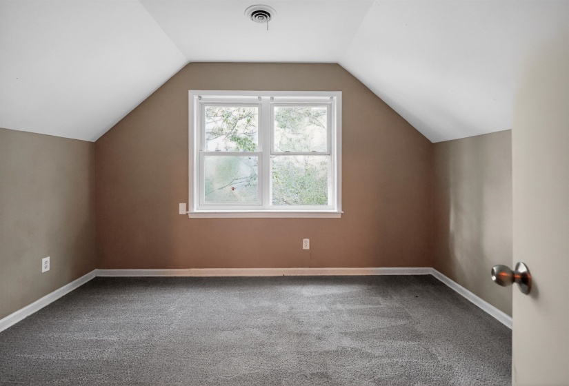 Spacious room featuring sloped ceilings, a double window, neutral wall paint, and gray carpet flooring