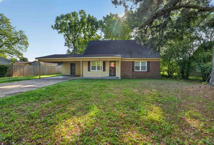 Ranch-style residence featuring a brick facade, carport, and mature trees framing the property