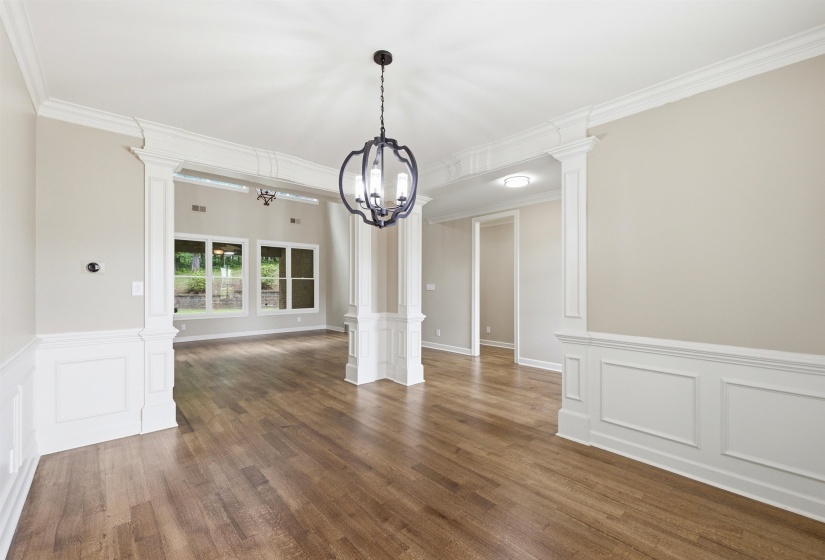 Open concept living space featuring wood-finish flooring, wainscoting, and crown molding