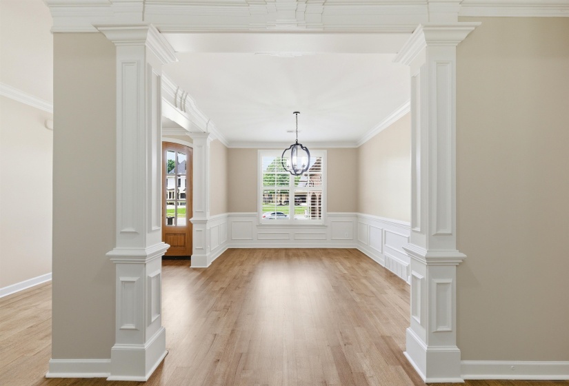 Spacious interior room featuring wood-finish flooring, wainscoting, and crown molding