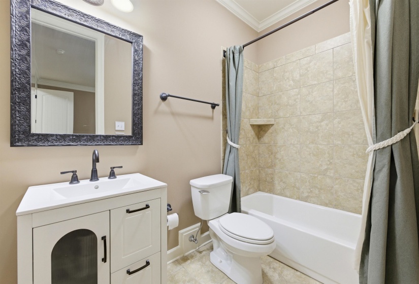 Bathroom featuring a white vanity with integrated sink, black hardware, and a framed mirror