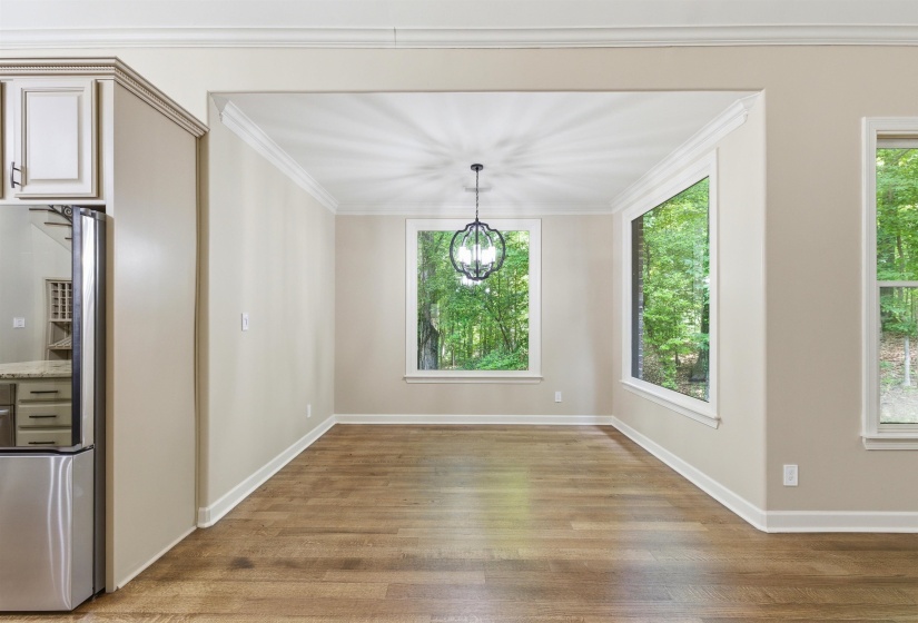Dining area featuring wood-finish flooring, a contemporary chandelier, and multiple large windows overlooking natural scenery