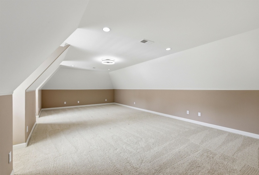 Spacious room featuring neutral carpeting, a two-tone wall treatment, recessed lighting, and a contemporary ceiling fixture