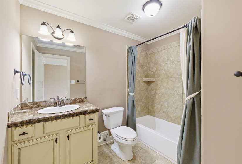 Bathroom featuring a vanity with a patterned countertop, undersink cabinetry, oval basin, and wall-mounted mirror