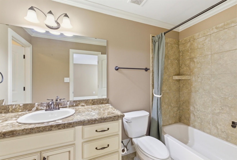 Bathroom featuring a single vanity with an oval undermount sink, a patterned countertop, and white cabinetry