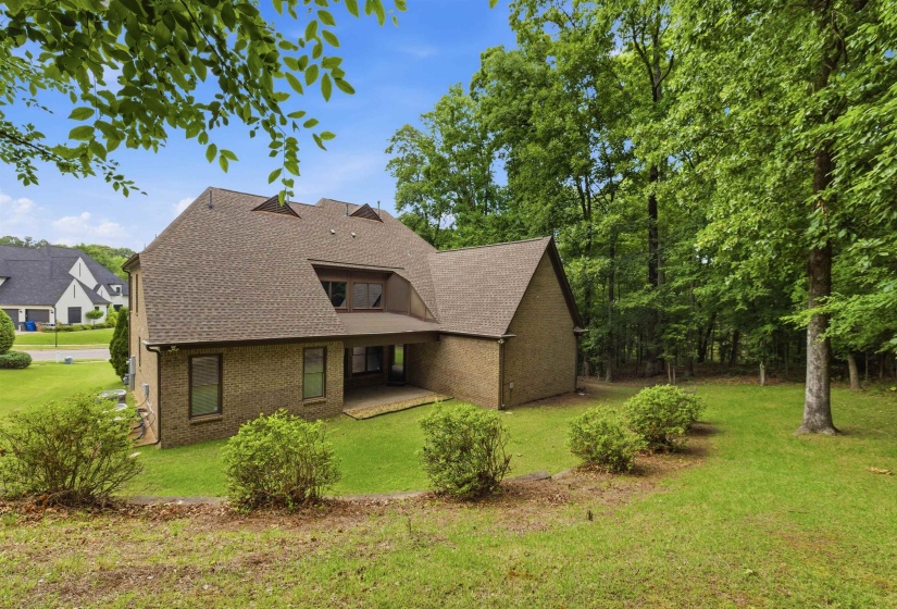 Brick exterior with a gabled roofline, multiple dormers, and an integrated covered patio