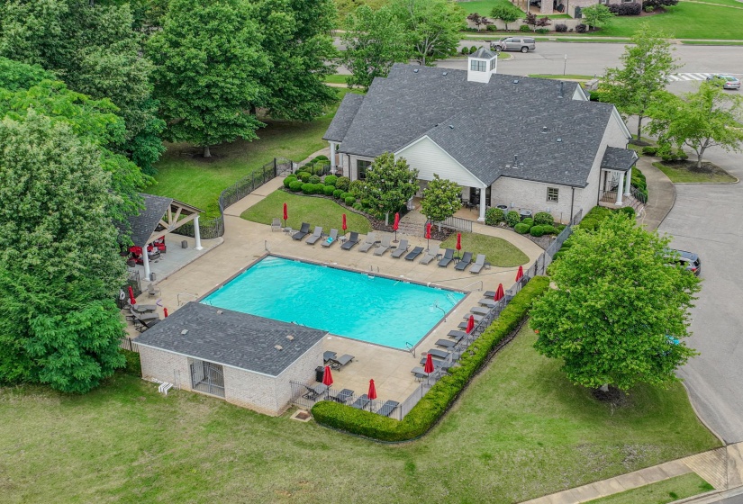 Community swimming pool with surrounding lounge chairs and red umbrellas