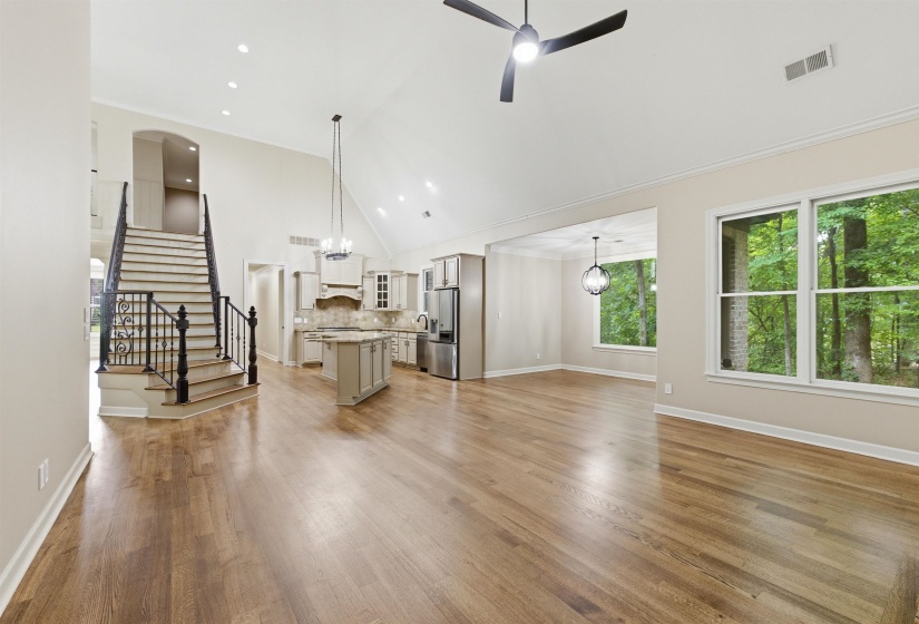Expansive open-concept living space featuring high vaulted ceilings, recessed lighting, and wood-finish flooring