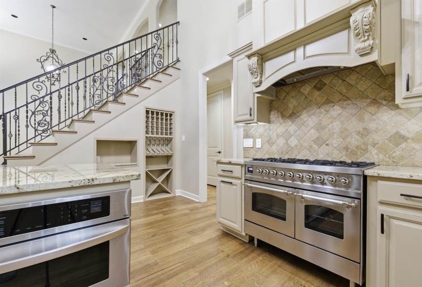 Gourmet kitchen with stainless steel double oven range, stone tile backsplash, and light-toned cabinetry