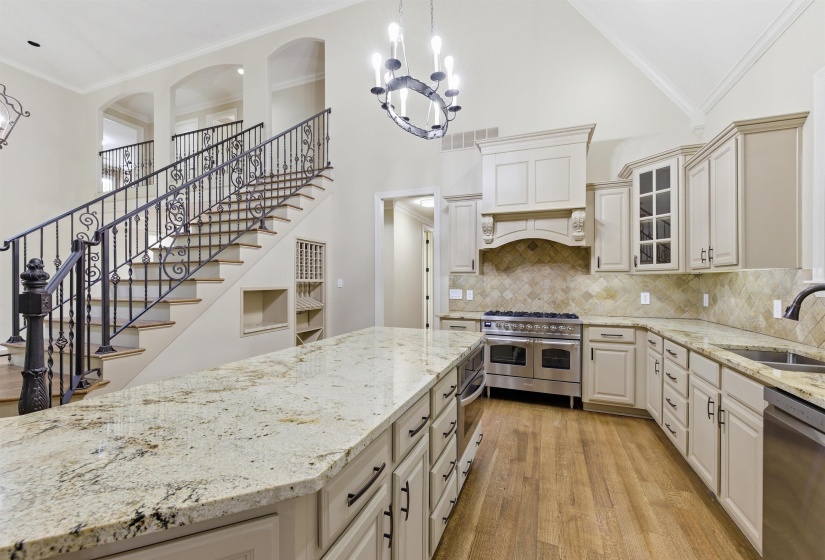 Spacious kitchen featuring a large island with light-toned countertops, custom cabinetry, a professional-grade range, and a tiled backsplash