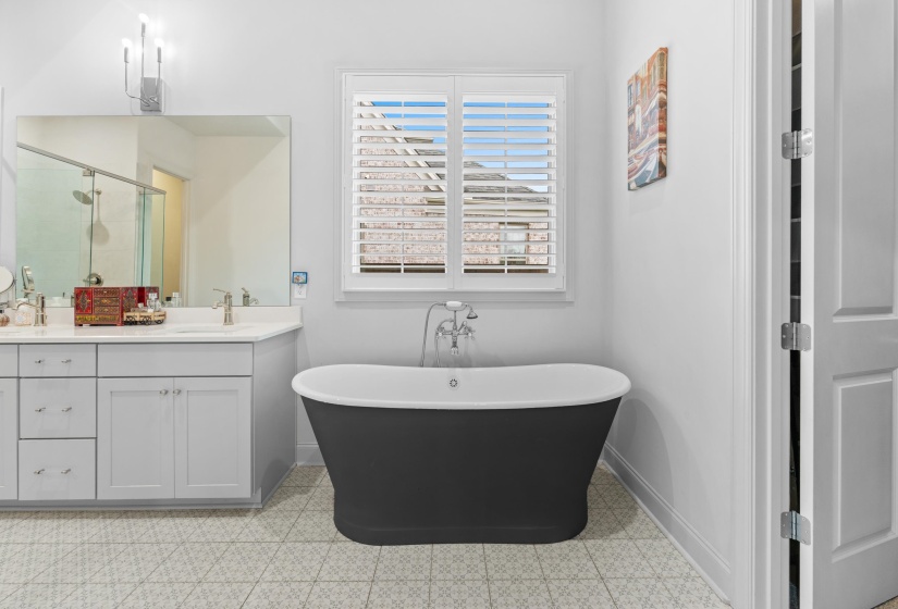 Freestanding black tub with floor-mounted faucet, complemented by a dual vanity with light gray cabinetry and white countertops