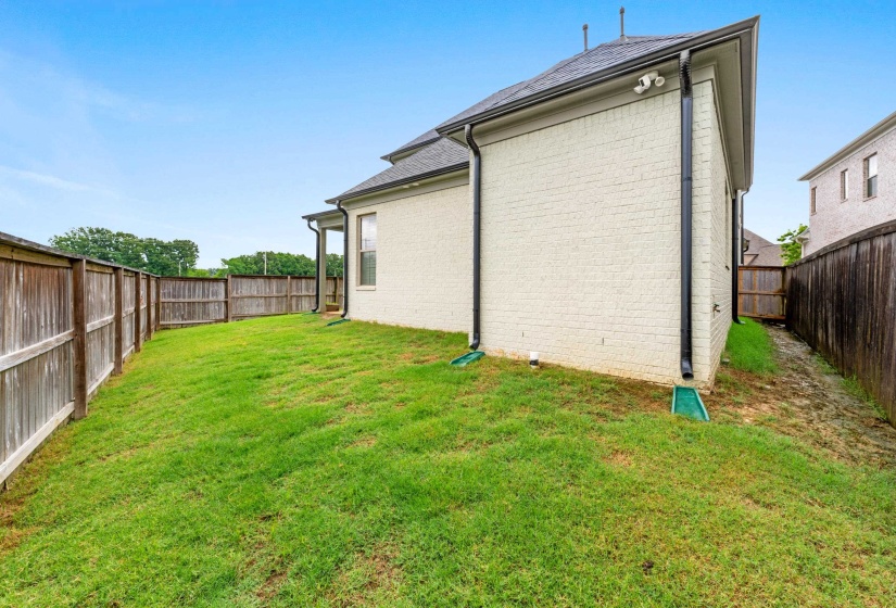 Rear exterior showcasing a brick facade, dark roofing, and perimeter fencing