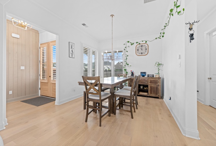Bright interior with light wood-finish flooring, white walls, and a modern chandelier