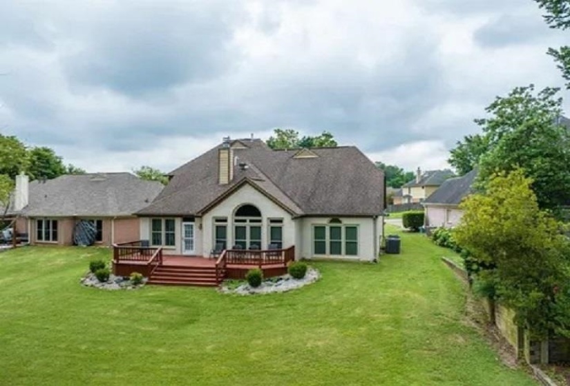 Rear exterior featuring a large, multi-level wooden deck with stairs leading to a spacious green lawn