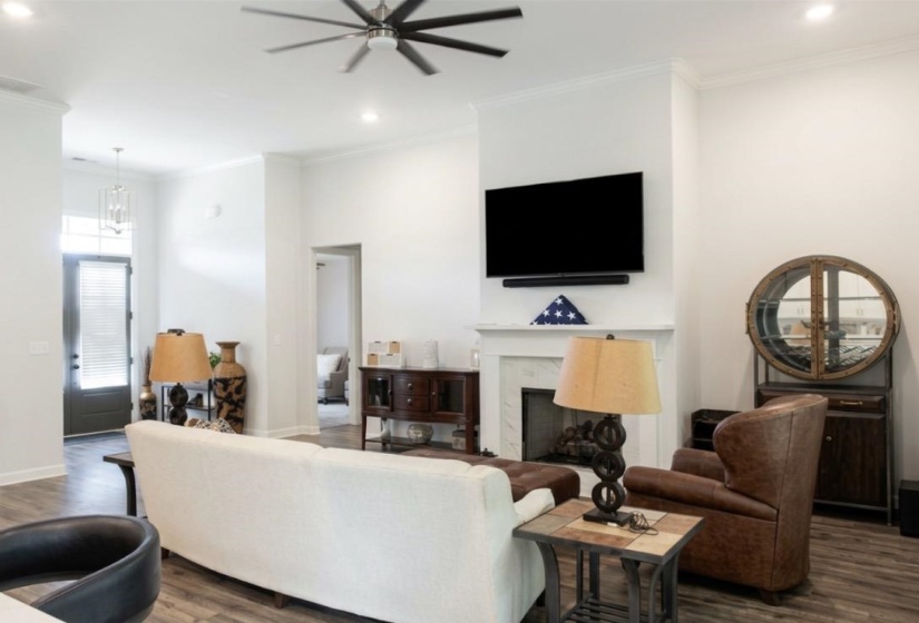 Spacious living area featuring a fireplace with a white mantel, recessed lighting, and a ceiling fan
