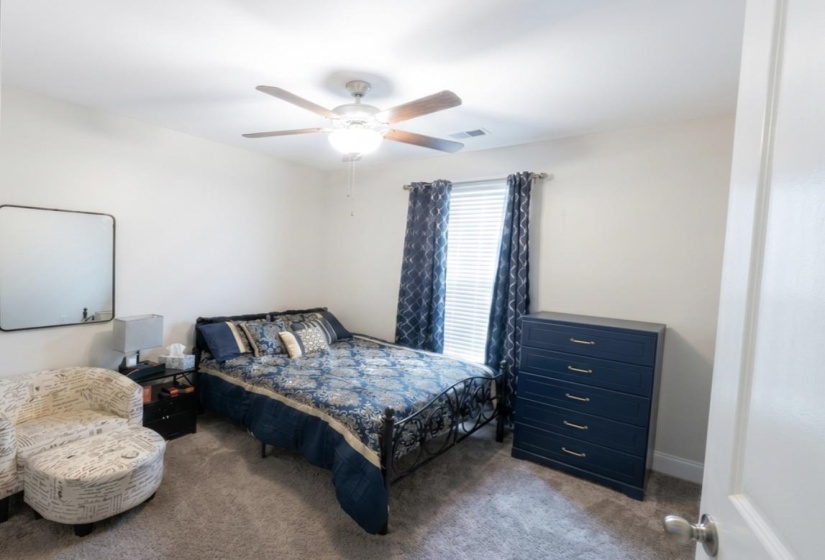 Carpeted room featuring a ceiling fan with light fixture, a window with blinds, and white walls