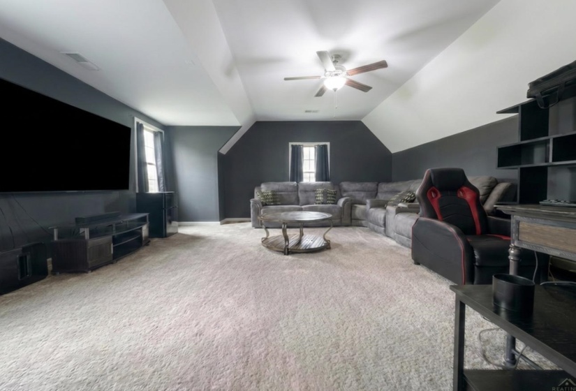 Spacious bonus room featuring plush carpeting, a multi-tone painted wall design, and a ceiling fan with integrated lighting