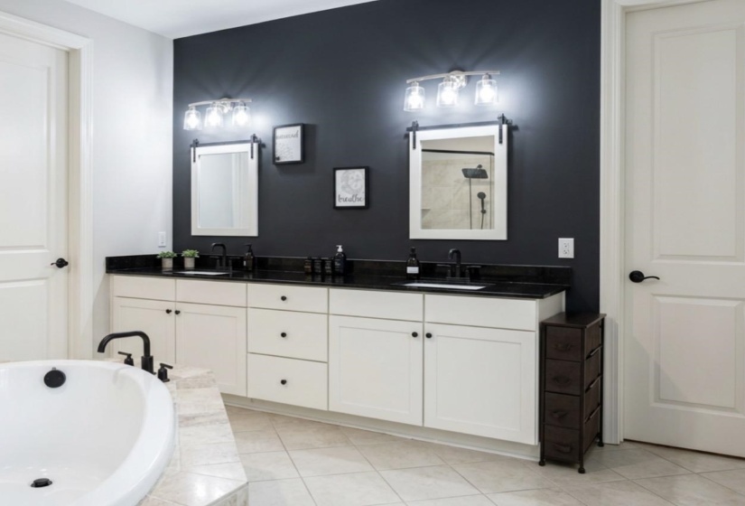 Double vanity featuring white cabinetry, black countertops, and matte black fixtures