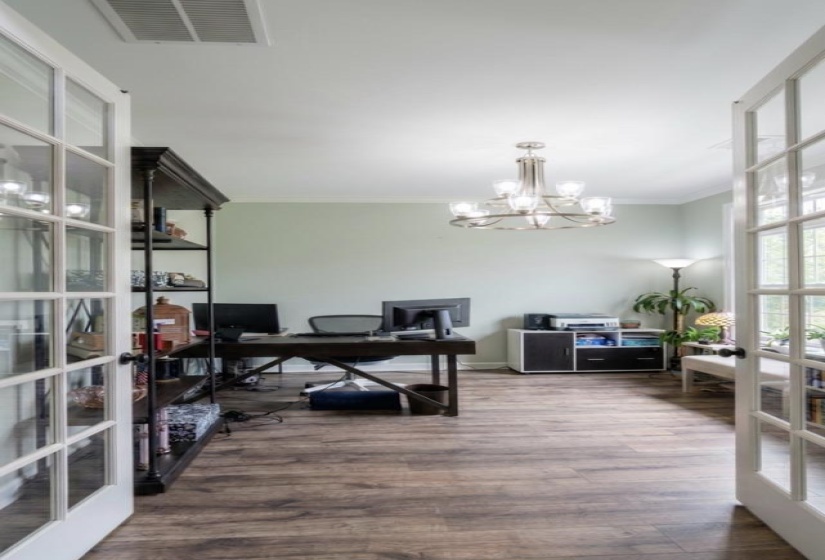 Room with wood-finish flooring, light green walls, and white crown molding