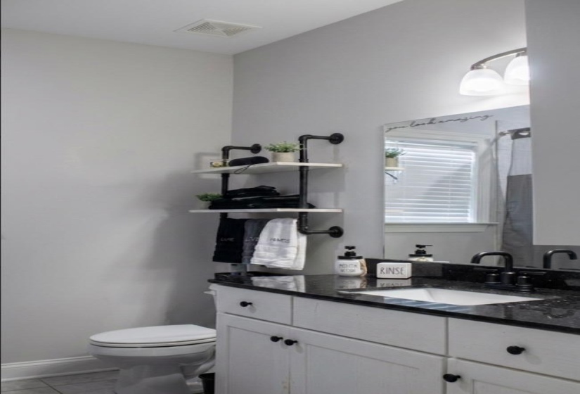 Bathroom featuring a white vanity with black hardware, a black countertop, and an undermount sink