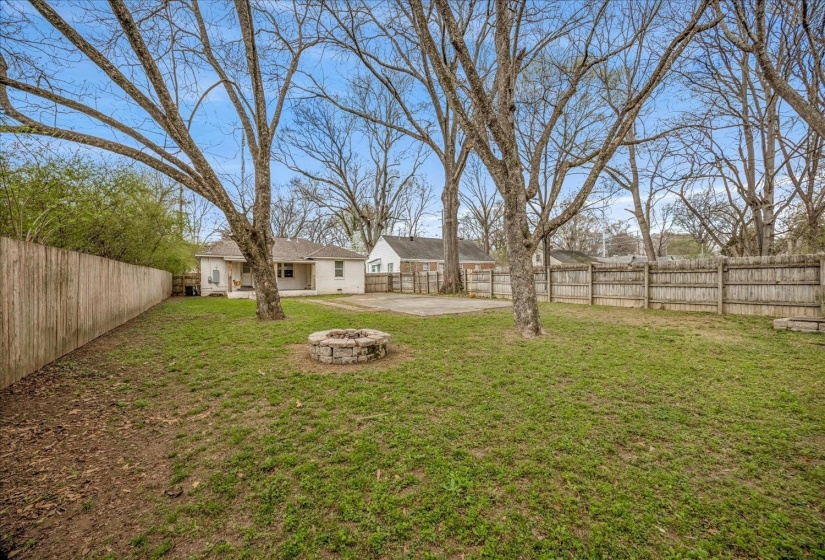 Fenced backyard with a patio and a fire pit