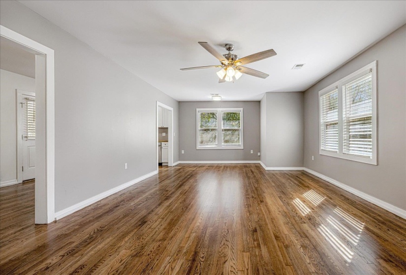 Unfurnished room featuring plenty of natural light, dark wood-style floors, and ceiling fan