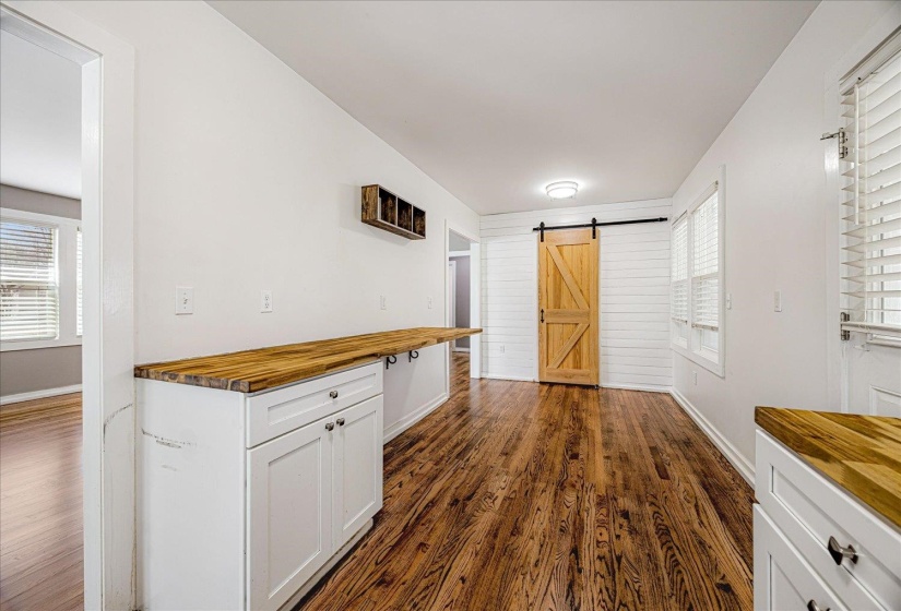 Kitchen featuring wood counters, a barn door, dark wood-type flooring, and white cabinetry
