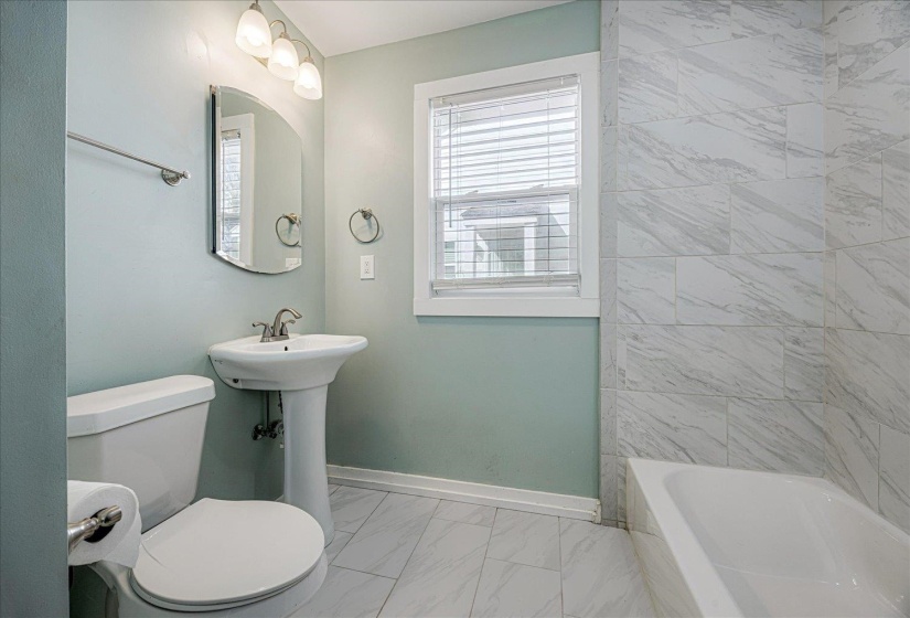 Full bath featuring light marble finish floors and  shower combination