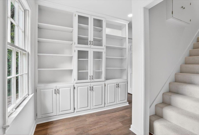 Built-in white cabinetry with glass-front uppers and ample shelving