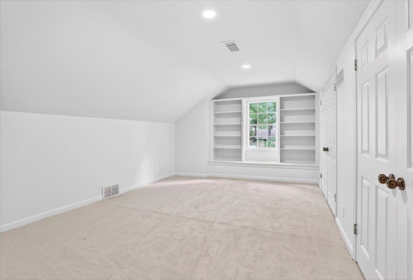 Bright room featuring built-in shelving, a central window, recessed lighting, and neutral carpeting