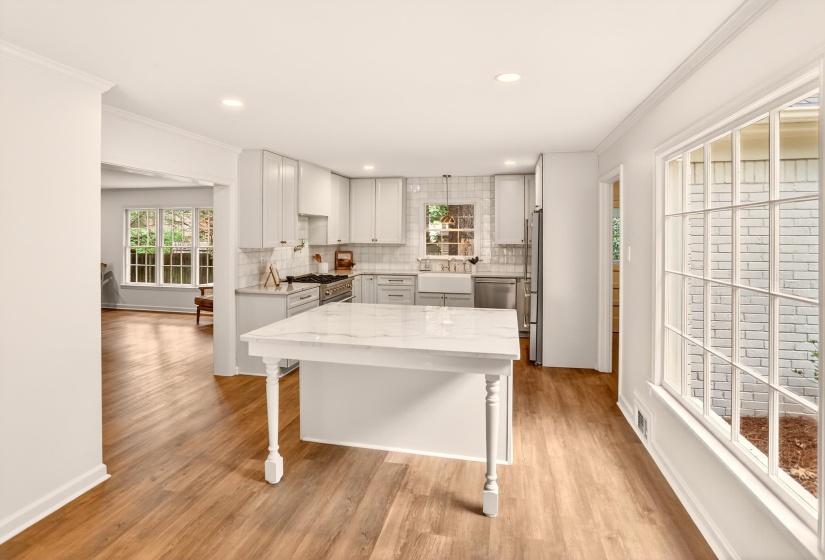 Bright kitchen featuring white shaker cabinetry, stainless steel appliances, a white subway tile backsplash, and an island with a white countertop