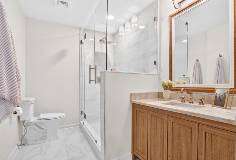 Bathroom featuring a frameless glass shower enclosure with subway tile surround, a built-in shower niche, and a rain shower head