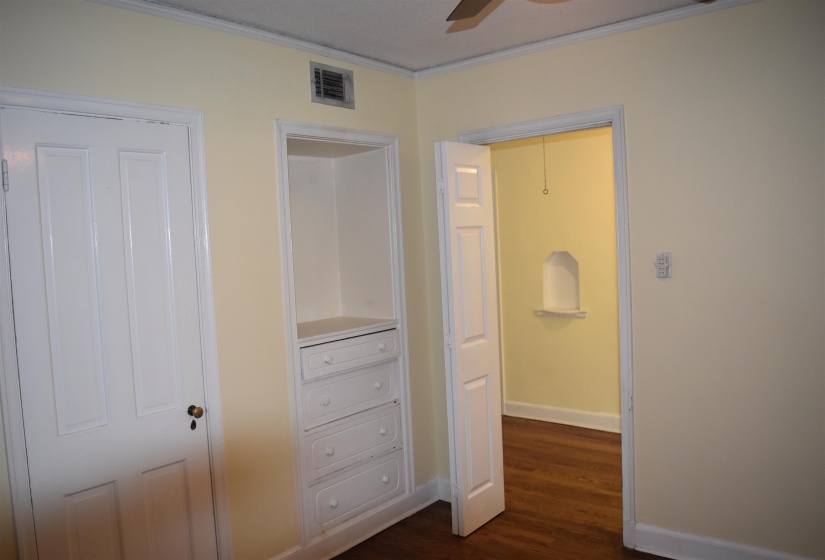 Hardwood flooring throughout, built-in storage with drawers, paneled interior doors, and crown molding