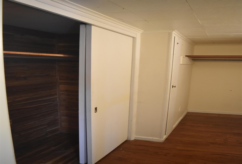 Closet space featuring sliding doors, a wood-finish interior wall, and a single wooden shelf