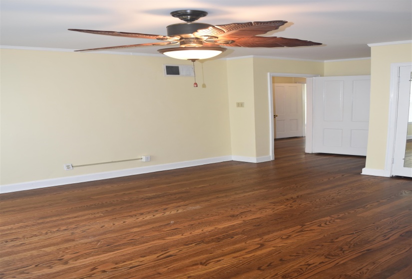 Hardwood flooring throughout featuring a ceiling fan with integrated lighting, white baseboards, and neutral wall tones