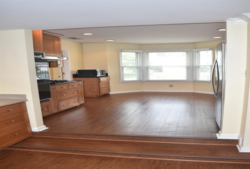 Open-concept kitchen featuring wood-finish flooring, recessed lighting, and a bay window