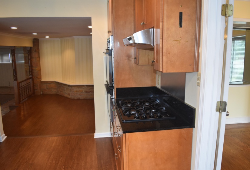 Kitchen area featuring wood cabinetry, integrated stainless steel appliances, a black gas cooktop, and black countertops
