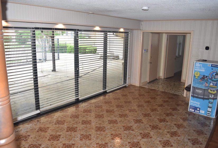 Room featuring patterned tile flooring, paneled walls, and recessed lighting