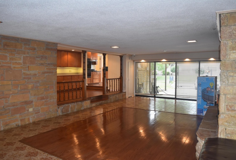 Spacious interior featuring wood-finish flooring, stone wall accents, and sliding glass doors