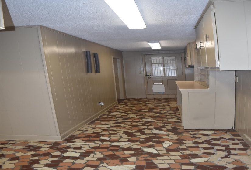 Hallway featuring mosaic tile flooring, panel walls, and a paneled door with glass inserts