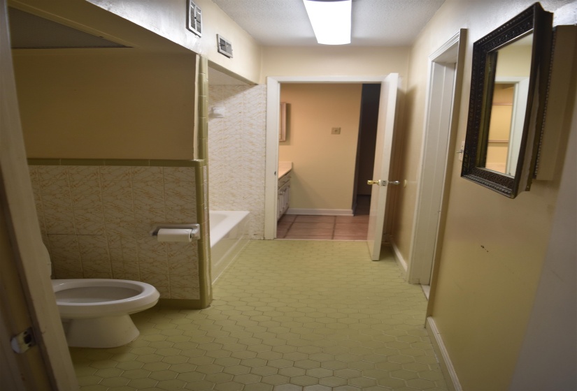 Bathroom featuring hexagon tile flooring, a built-in tub with partial wall tile surround, and a white toilet