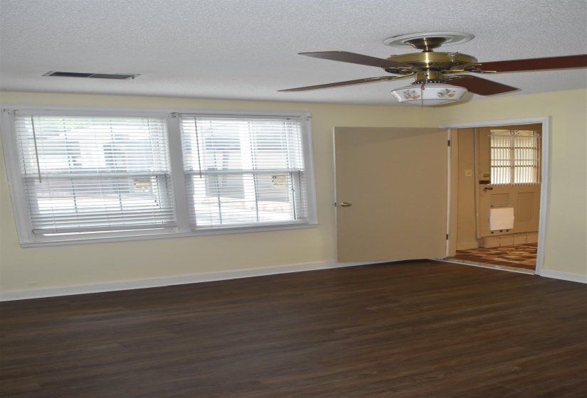 Room featuring wood-finish flooring, light yellow painted walls, and a white popcorn ceiling