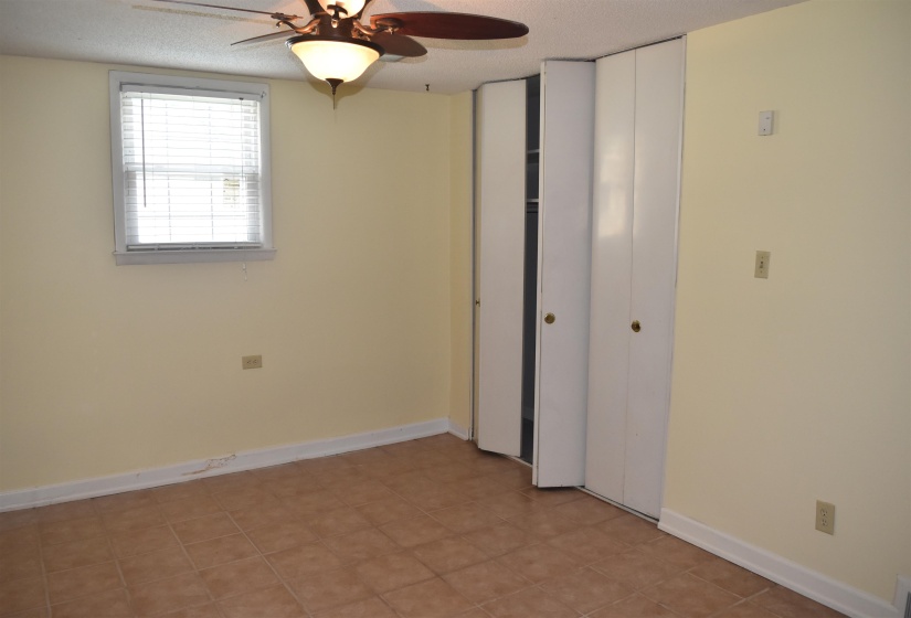 Room featuring neutral-toned walls, tile flooring, a window with horizontal blinds, and a ceiling fan with integrated lighting