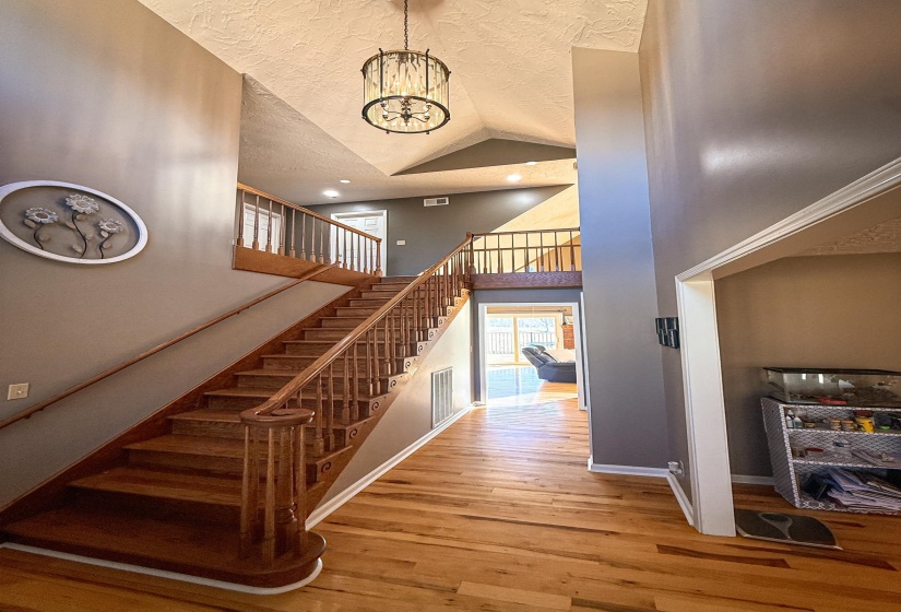 Vaulted entryway featuring a prominent wood staircase with balusters and handrails