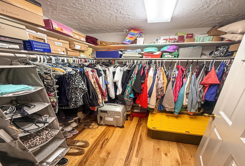Spacious closet with wood-finish flooring, white wire shelving, and extensive hanging rod storage
