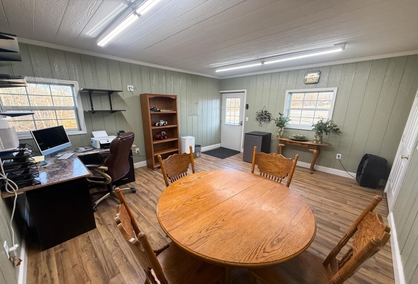 Versatile room featuring wood-finish flooring, light green paneled walls, and multiple windows for natural illumination